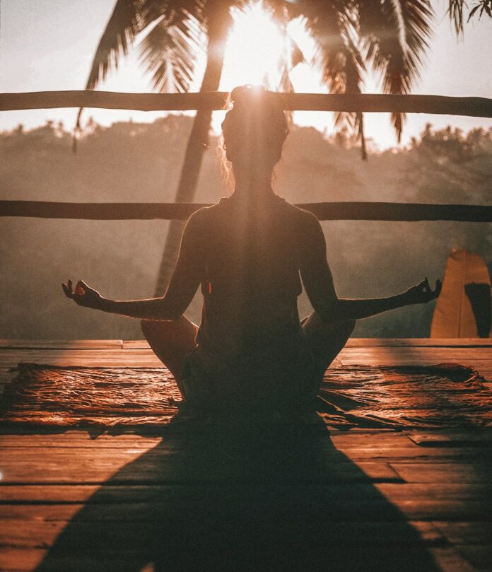 Photo by Jared Rice woman doing yoga meditation on brown parquet flooring