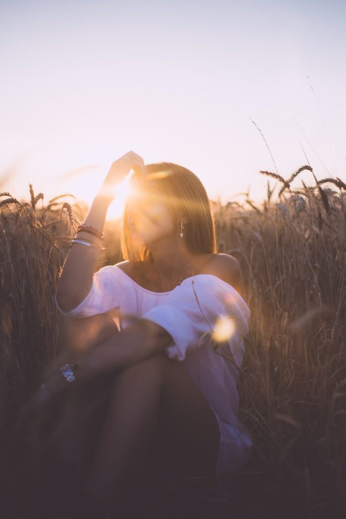 Photo by Matteo Vistocco woman sitting on grass field during sunset