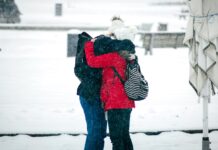 오늘은 어떤 뜻 깊은 일을 해볼까? person in red and black jacket and black pants carrying white dog on snow covered ground