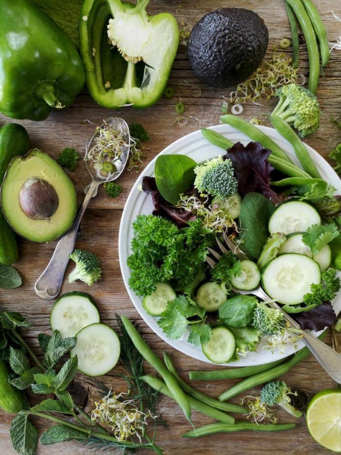 Photo by Nadine Primeau sliced broccoli and cucumber on plate with gray stainless steel fork near green bell pepper, snowpea, and avocado fruit