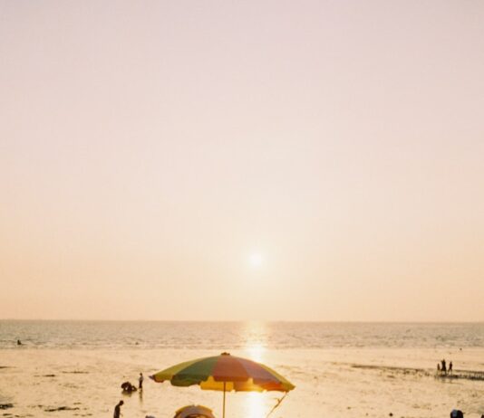 “피부가 따가워요, 햇빛 때문일까요?”… 여름철 자외선이 피부를 망가뜨리는 5가지 방식 a beach with people and umbrellas