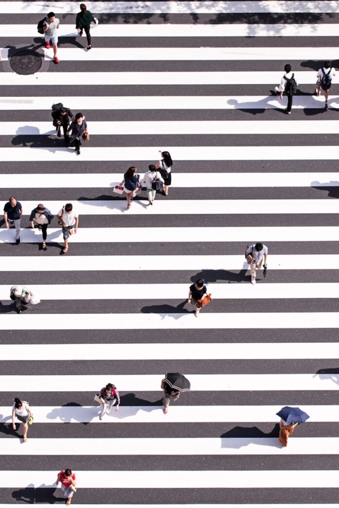 Photo by Ryoji Iwata aerial view photography of group of people walking on gray and white pedestrian lane
