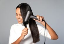집에서도 건강한 두피와 머릿결…최근 떠오르는 ‘마이크로 관리’ 트렌드 a woman blow drying her hair with a hair dryer