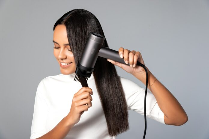 Photo by TYMO Beauty a woman blow drying her hair with a hair dryer
