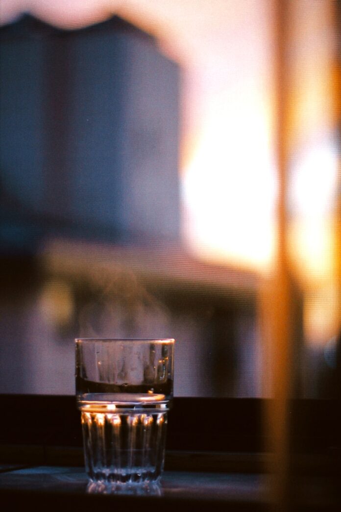 a glass of water sitting on a window sill