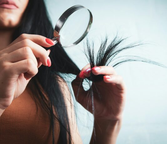 머릿결도 건강해야 아름답다…일상 속 실천하는 ‘두피·모발 관리법’ 주목 Woman examining split ends of hair with magnifying glass