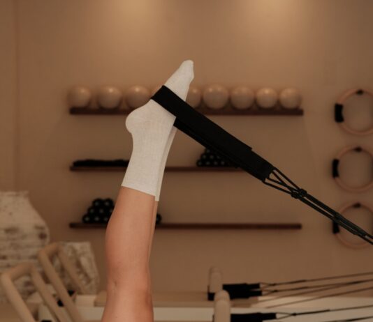 집과 일상 속으로 들어온 필라테스, 건강 트렌드의 새로운 중심 Woman does pilates exercise on a reformer machine.